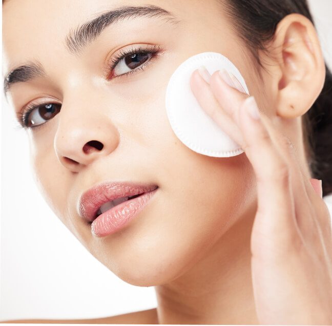 Femme appliquant un disque démaquillant blanc sur sa joue, soins de la peau et bien-être